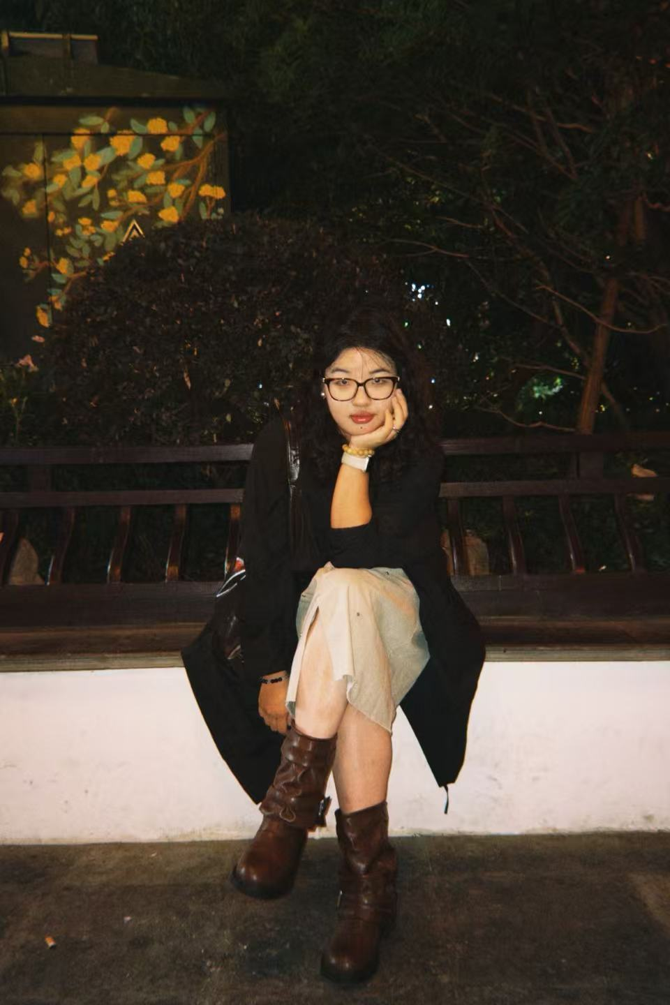 Portrait of Jora Lu seated in a quiet garden at night